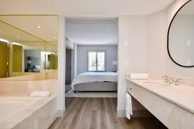 a bathroom with two sinks and a bedroom with a bed at Lux Jacuzzi Suite - Top Level in Shanty Bay