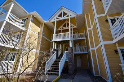 a yellow apartment building with white balconies and stairs at Lux Jacuzzi Suite - Top Level in Shanty Bay