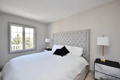 a white bedroom with a large bed and a window at Lux Jacuzzi Suite - Top Level in Shanty Bay