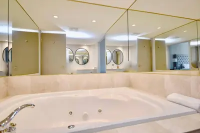 a large bath tub in a bathroom with mirrors at Lux Jacuzzi Suite - Top Level in Shanty Bay