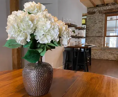 a vase with white flowers sitting on a table at Stone Mill Retreat - Rustic Cozy Getaway with Loft! in Fergus