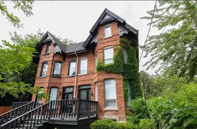 a large brick house with ivy on it at Grand 3 BR Toronto Victorian Entire Home in Toronto