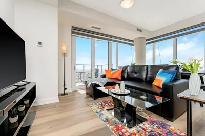 a living room with a black leather couch and a table at Newly Built Condo with Amazing Views in Kitchener