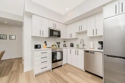 a white kitchen with white cabinets and appliances at Modern High Rise King bed Condo with Private Balcony in Kitchener