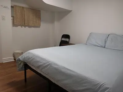 a bedroom with a large bed with white sheets at Cozy Private Rooms in Basement in Richmond Hill