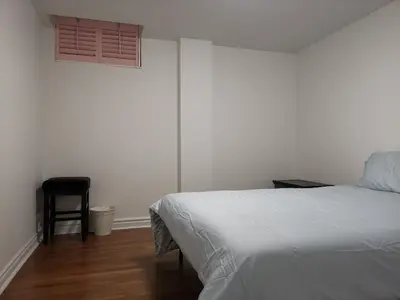 a bedroom with a bed and a chair and a window at Cozy Private Rooms in Basement in Richmond Hill