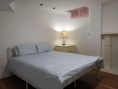 a bedroom with a bed and a lamp on a night stand at Cozy Private Rooms in Basement in Richmond Hill