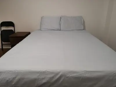a large white bed in a room with a chair at Cozy Private Rooms in Basement in Richmond Hill