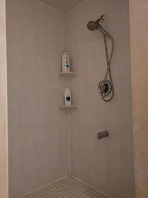 a bathroom with a shower with two shelves on the wall at Cozy Private Rooms in Basement in Richmond Hill