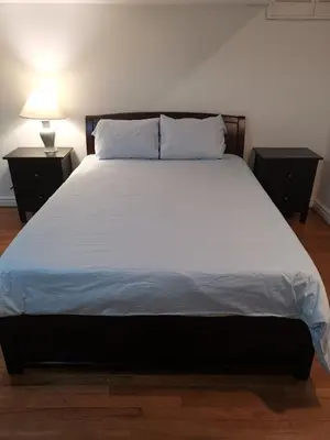 a large bed in a room with two nightstands and a bed sidx sidx at Cozy Private Rooms in Basement in Richmond Hill