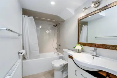 a bathroom with a sink and a toilet and a mirror at Midtown 2 Bedroom Apartment in Toronto