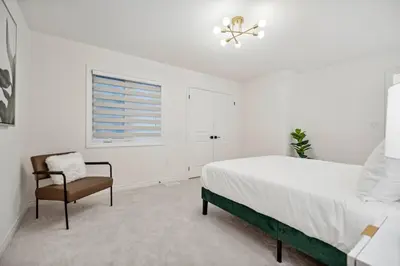a white bedroom with a bed and a chair at Luxury Vacation Home Near Lake Pool Table in Barrie