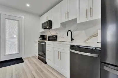 a kitchen with white cabinets and stainless steel appliances at Luxe Lodges Lake Erie in Port Dover