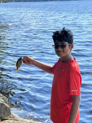 a young boy holding a fish in the water at Birkswyld waterfront cottage Mary Lake in Huntsville