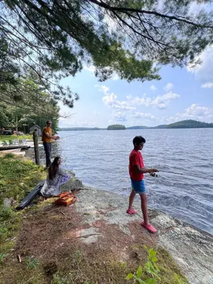 two people standing on a rock near a body of water at Birkswyld waterfront cottage Mary Lake in Huntsville