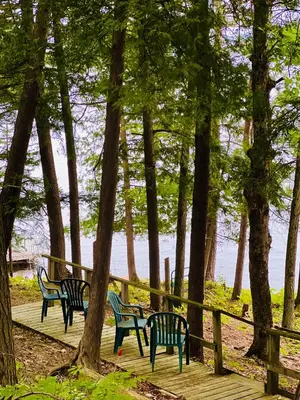 a group of benches sitting on a boardwalk near the water at Birkswyld waterfront cottage Mary Lake in Huntsville