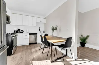 a white kitchen with a wooden table and chairs at RentX 3Bed Cozy Home - Hospital GO 2ParkingWi-Fi in Hamilton
