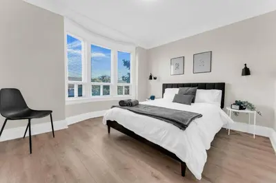 a white bedroom with a bed and a chair at RentX 3Bed Cozy Home - Hospital GO 2ParkingWi-Fi in Hamilton