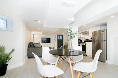 a kitchen and living room with a table and white chairs at RentX Modern Suite - Near GO Hospital Parking in Hamilton