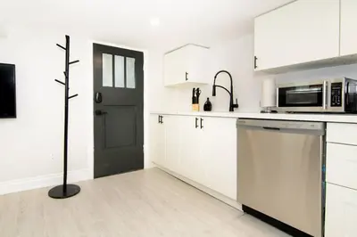 a kitchen with white cabinets and a black door at RentX Modern Suite - Near GO Hospital Parking in Hamilton