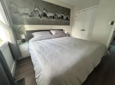 a bedroom with a bed with a painting of zebras at Lonborough Ave Upstairs in Toronto