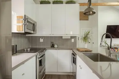 a white kitchen with white cabinets and a sink at Lonborough Ave Upstairs in Toronto
