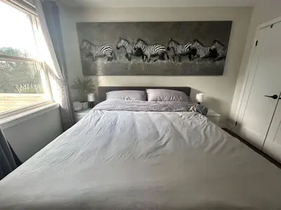 a bed in a bedroom with a painting of zebras at Lonborough Ave Upstairs in Toronto