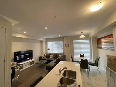 a kitchen and living room with a couch and a tv at Cozy 3-Bedrooms T-Home #Niagara in Thorold
