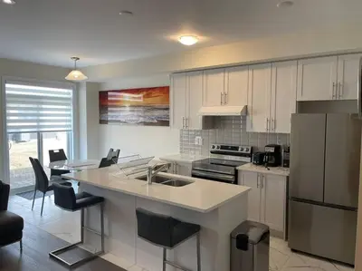 a kitchen with white cabinets and a kitchen island with a sink at Cozy 3-Bedrooms T-Home #Niagara in Thorold