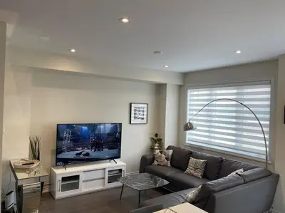a living room with a couch and a flat screen tv at Cozy 3-Bedrooms T-Home #Niagara in Thorold