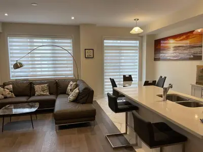 a living room with a couch and a kitchen at Cozy 3-Bedrooms T-Home #Niagara in Thorold