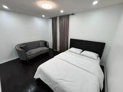 a bedroom with a large bed and a couch at Entire bungalow, full privacy, free parking in Oshawa