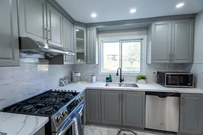 a kitchen with white cabinets and a stove and a sink at Chic and Cozy 5 Bedroom House in Brampton