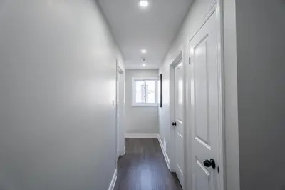a hallway with white walls and a window at Chic and Cozy 5 Bedroom House in Brampton