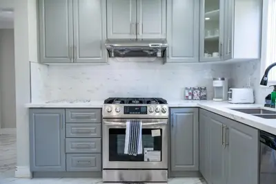 a kitchen with white cabinets and a stove at Chic and Cozy 5 Bedroom House in Brampton