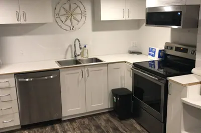 a kitchen with white cabinets and a sink and a stove at Affordable 2BR Family Friendly Basement Apt in Bowmanville