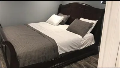 a bed with a wooden headboard and pillows on it at Affordable 2BR Family Friendly Basement Apt in Bowmanville
