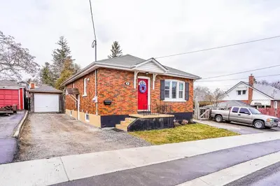 a brick house with a red door on a street at Affordable 2BR Family Friendly Basement Apt in Bowmanville