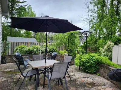 a table and chairs with an umbrella on a patio at Nancy by the Bay Wasaga Beach in Wasaga Beach