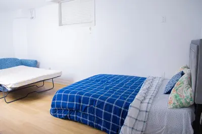 a bedroom with a bed and a chair and a window at Cozy Haven 2 bedroom Basement apartment with Treated water in London