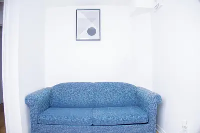 a blue couch in a room with a picture at Cozy Haven 2 bedroom Basement apartment with Treated water in London