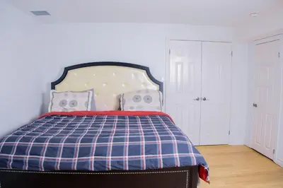 a bedroom with a bed with a blue and white plaid blanket at Cozy Haven 2 bedroom Basement apartment with Treated water in London