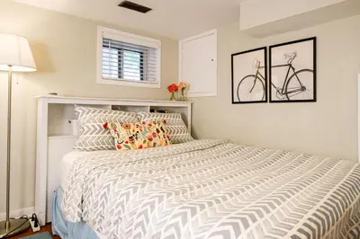 a bedroom with a white bed with a bike on the wall at Charming Basement Suite with Private Entrance Near Subway, Koreatown & UofT in Toronto