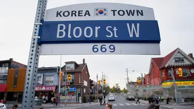 a street sign on a pole on a city street at Charming Basement Suite with Private Entrance Near Subway, Koreatown & UofT in Toronto