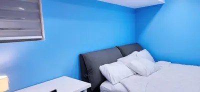 a bed in a room with a blue wall at Garden Avenue Homes Free Parking in Brantford