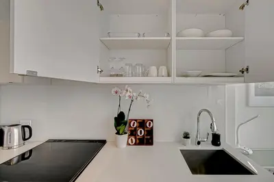 a white kitchen with a sink and white cabinets at The Cityscape by Instant Suites - PentHouse Unit in Toronto