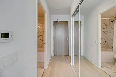 a white bathroom with a tub and a glass door at The Cityscape by Instant Suites - PentHouse Unit in Toronto