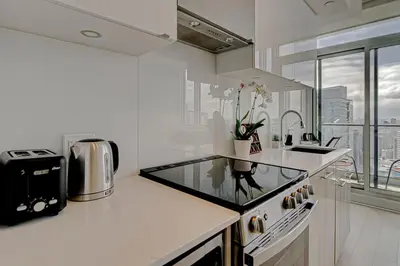 a white kitchen with a sink and a counter top at The Cityscape by Instant Suites - PentHouse Unit in Toronto