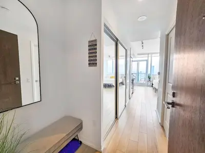 a hallway with white walls and a bench and a mirror at The Cityscape by Instant Suites - PentHouse Unit in Toronto