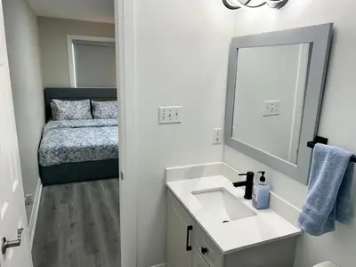 a bathroom with a sink and a mirror and a bed at Treasure Haven Near Tourism Barrie in Barrie